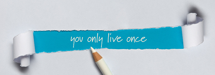 YOLO (You Only Live Once) written under torn paper.