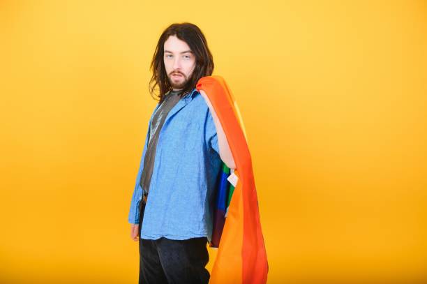 istock Handsome young man with pride movement LGBT Rainbow flag on shoulder against white background. Man with a gay pride flag. 1452339417