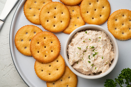 Tuna spread in white bowl with Butter cracker in white plate.Top view