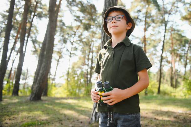 istock Boy with binoculars. Kid in green forest at summer daytime together. 1452341804