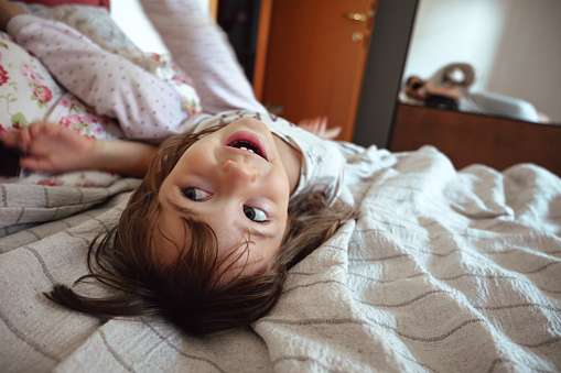 toddler girl having fun in a bed at home.