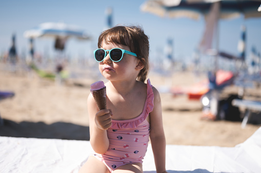 little girl eating ice cream on the beach. Chaise Longue,\nCheerful,\nChildhood,