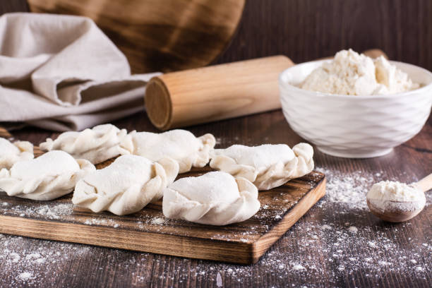 istock Raw dumplings on a cutting board and flour on the table. Home cooked food. 1452347151