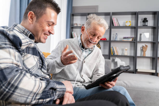 l'uomo anziano prende aiuto in tablet digitale da un giovane uomo - grandparent senior adult child reading foto e immagini stock