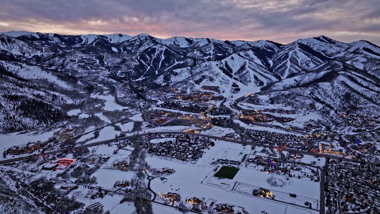 Park City Utah Aerial v32 cinematic panning view capturing highway road leading to snyderville townscape and surrounding quarry mountain landscape at dusk - Shot with Mavic 3 Cine - February 2022