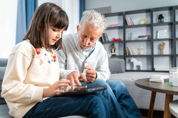 l'uomo anziano prende aiuto in tablet digitale da sua nipote - grandparent senior adult child reading foto e immagini stock