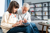 Senior man takes help in digital tablet from his granddaughter
