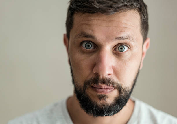 Portrait of surprised man standing against a grey background stock photo