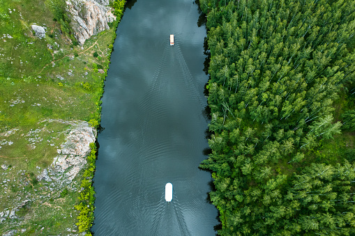 drone view of the river among the forest. landscape of the river and boats floating on the river. summer day, water transport