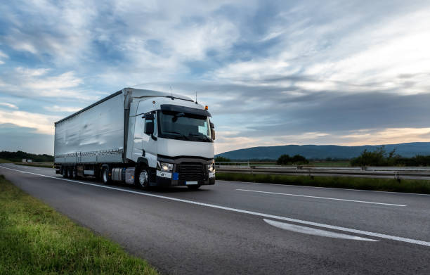 White Truck on the highway Big White truck driving on the highway through countryside landscape at sunset. truck stock pictures, royalty-free photos & images