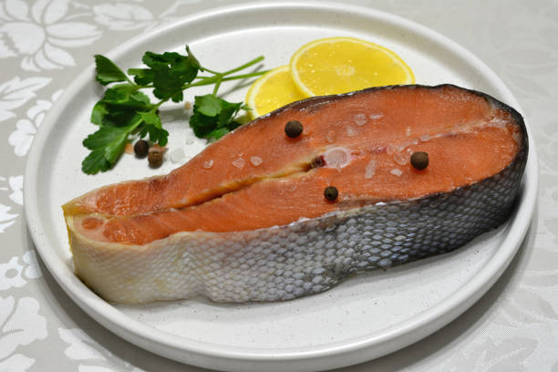 raw salmon steak on white tray with lemon and allspice isolated, macro