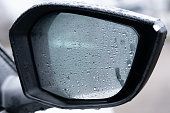Car wing mirror wet with raindrops