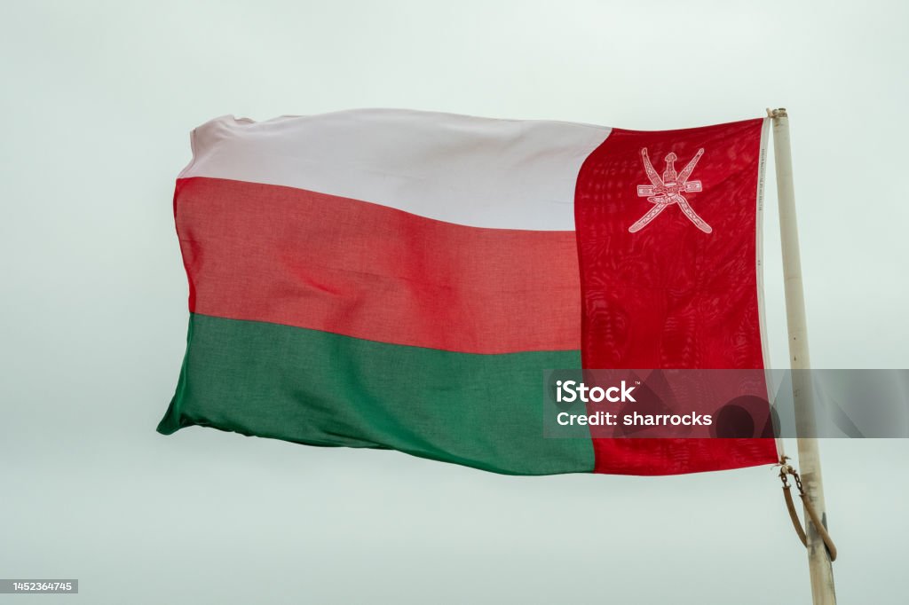 Flag of Oman Flag of Oman flying from a pole on a grey drab day All Middle Eastern Flags Stock Photo