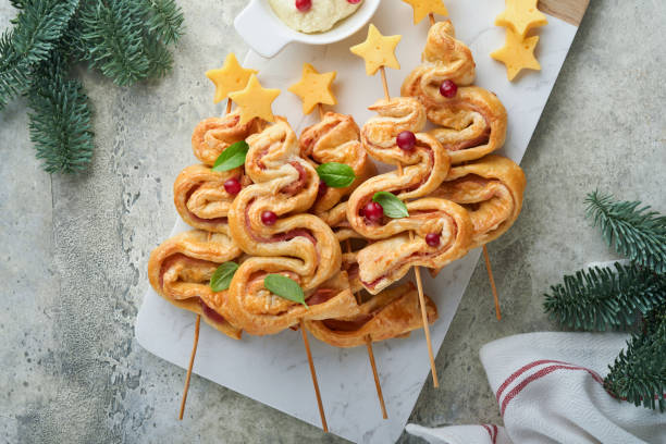 istock Christmas or New Year appetizer. Christmas tree shape puff pastry buns with cheese and ham. Group of Christmas tree shapes on marble stand. Festive idea for Christmas or New Year dinner. Top view. 1452365277