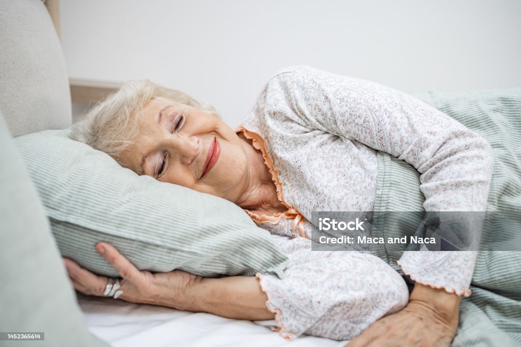 Senior woman sleeping in bed Photo of a smiling senior woman sleeping in bed Sleeping Stock Photo