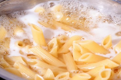 Cooking pasta. Penne boiling in the hot water.