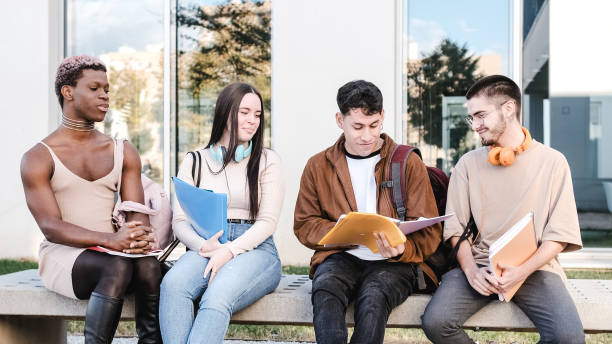Group of friends sitting in line outside the university discussing class notes stock photo