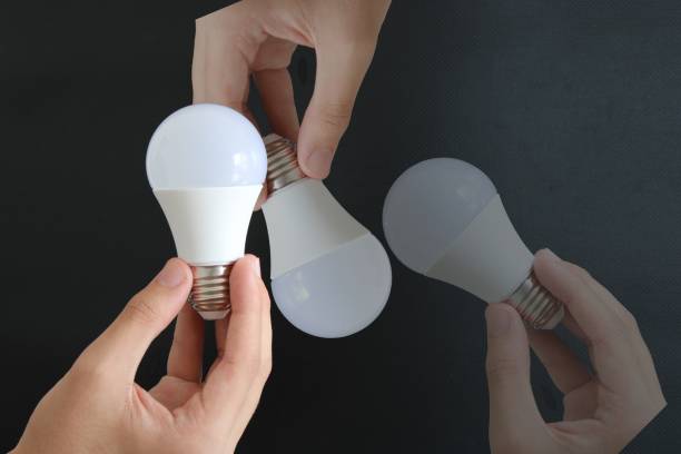 istock man holding light bulb on black background. electricity and savings 1452374350
