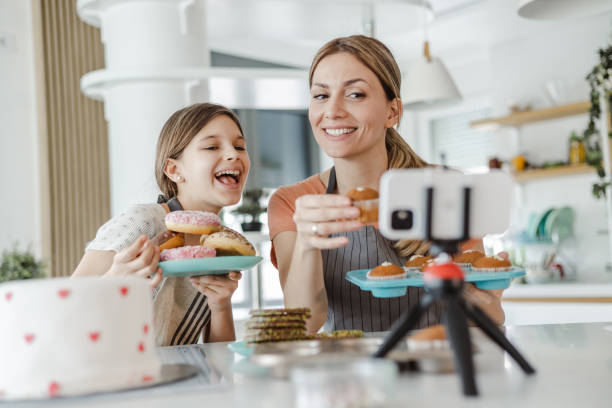 Female vlogger filming a tutorial together with her daughter about decorating a sweets
