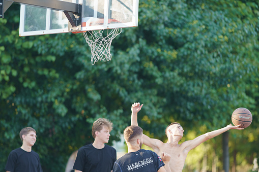 Moscow, Russia - August 5, 2022: Basketball basket and sport team it in summer day. Man threw the ball into the basket. Healthy lifestyles of youth. Sports competitions on the sports ground.