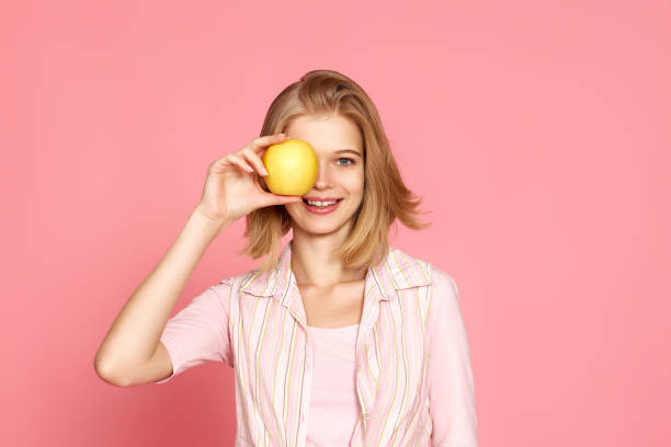 istock blonde woman covers one eye with fresh apple 1452378853
