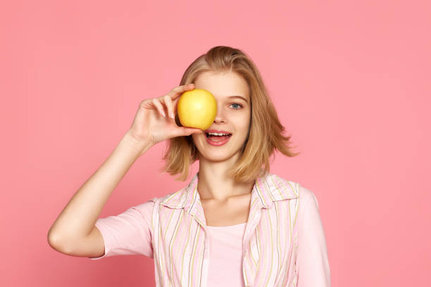 istock blonde woman covers one eye with fresh apple 1452378855