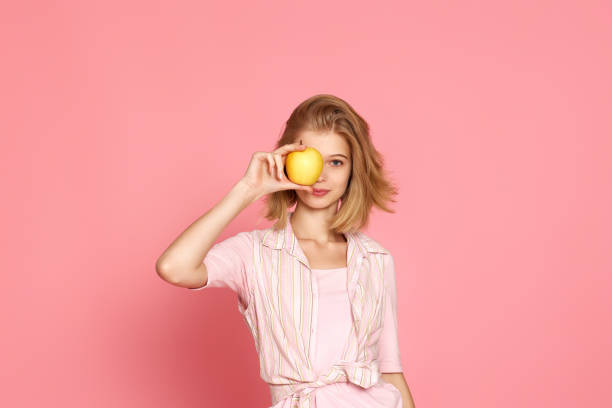 istock blonde woman covers one eye with fresh apple 1452378860