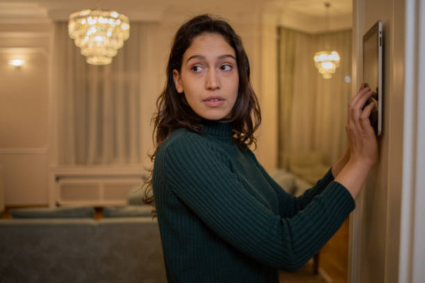 istock Young woman adjusts the temperature at home with a device on the wall 1452380141