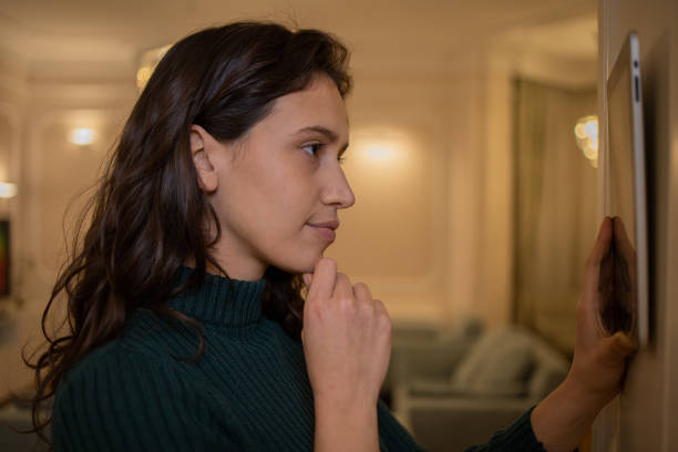 istock Young woman adjusts the temperature at home with a device on the wall 1452380146