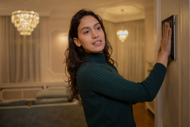 istock Young woman adjusts the temperature at home with a device on the wall 1452380147