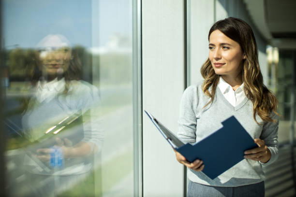 Portrait d’une femme d’affaires prospère debout dans un couloir avec bloc-notes - Photo