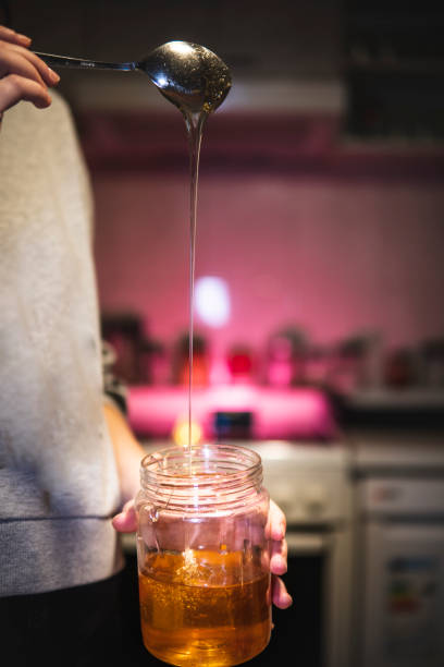 istock Caucasian girl scoops out honey with a spoon 1452387277