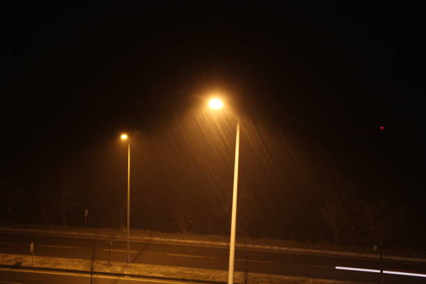 istock image of snow or rain falling at night in electric pole light 1452390501