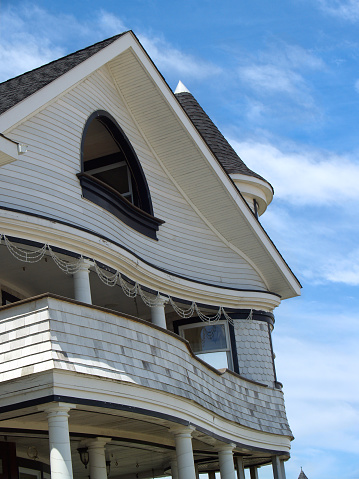 A unique old Victorian Revival house by the sea in historical coastal town of Ocean Grove, New Jersey, USA (part of series of 3 different views of this home) Photograph is in vertical orientation and was photographed with a DSLR on a clear day with azure skies. The home has a turret, white stained wood shingles, and unique curves. 