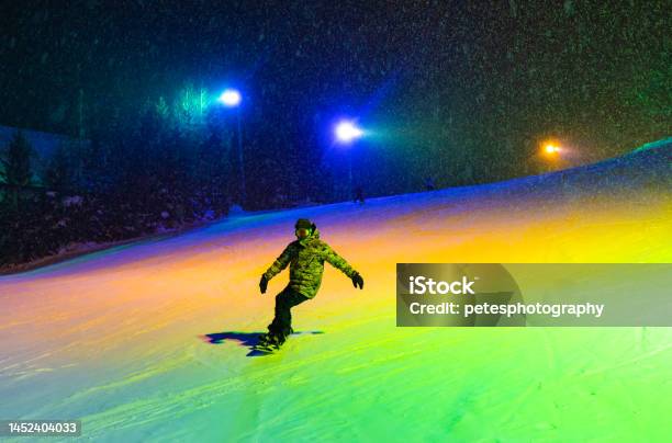 Illuminated Night Snowboarding Under Colorful Lights Stock Photo - Download Image Now