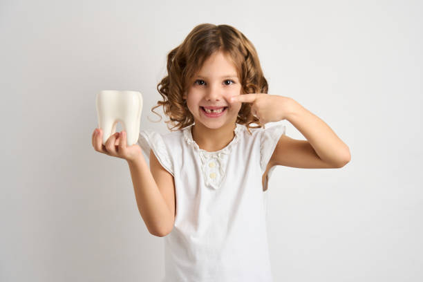 Portrait of happy girl with white teeth, close-up Little girl holding tooth on a white background with copy space. Portrait of happy girl with white teeth, close-up pediatric dentistry stock pictures, royalty-free photos & images