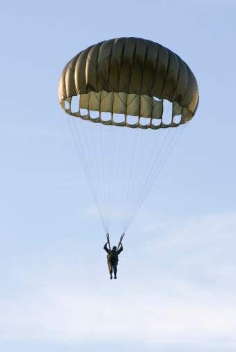 Paratroopers jump out of an old military biplane
