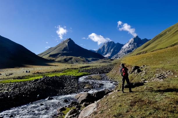 istock Man in the rocky mountains covered with green grass and a river 1452413446