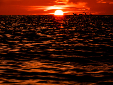 Orange sunset in the sea, touristic Thai boats watching the sunset in the sea