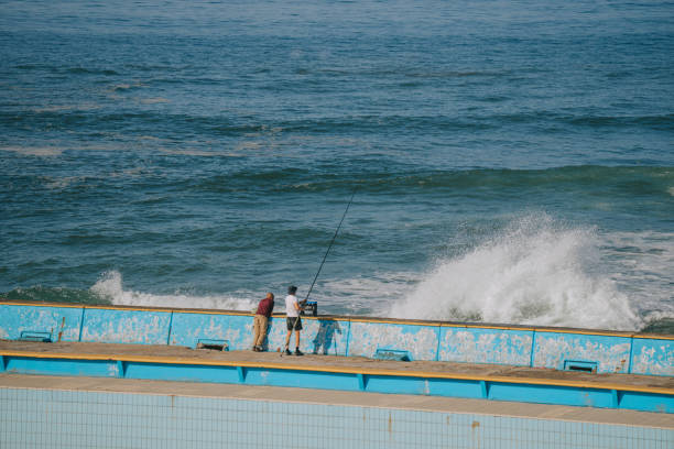 Tourist fishing at Casablanca, Morocco beach with strong breaking waves on November 14th year 2022 Tourist fishing at Casablanca, Morocco beach with strong breaking waves on November 14th year 2022 casablanca stock pictures, royalty-free photos & images