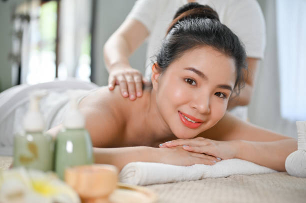 istock Beautiful Asian woman lying on spa massage table, getting back massage by a Thai masseur 1452420603