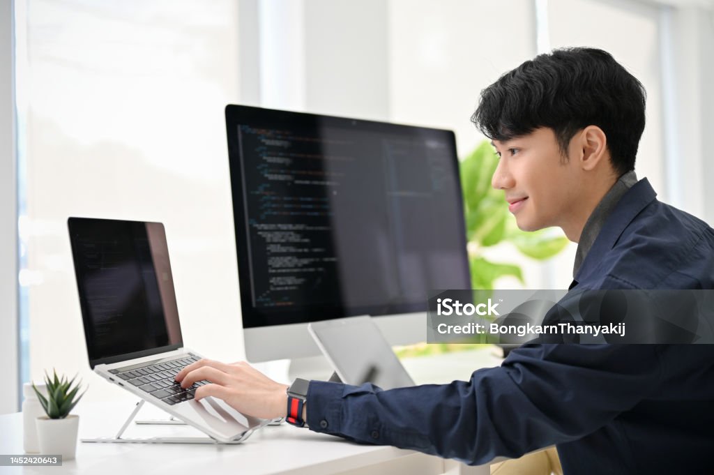 Smart Young Asian Male Programmer Coding At His Desk Using Laptop And ...