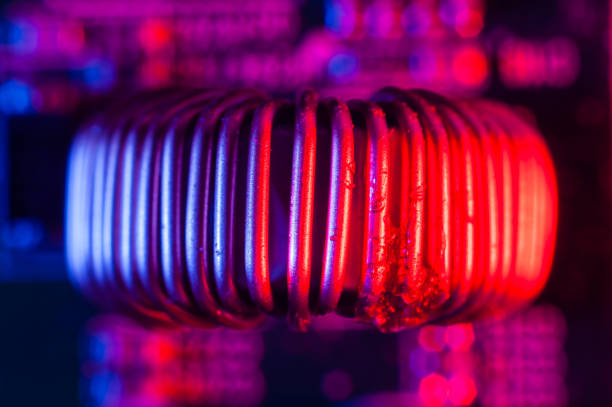 istock Single copper induction coil with copper wire on electronic PCB close up in red and blue lighting 1452424686