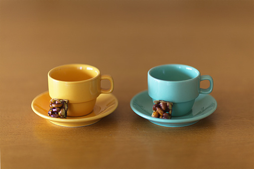 Two empty espresso cups on a wooden table with a piece of candy placed on saucers