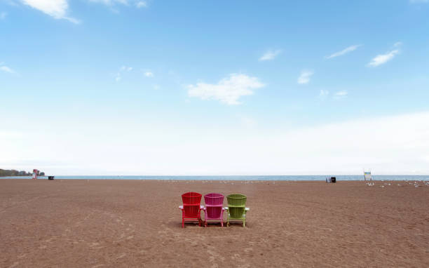 Three Multicoloured Chairs in a Row at the Beach stock photo