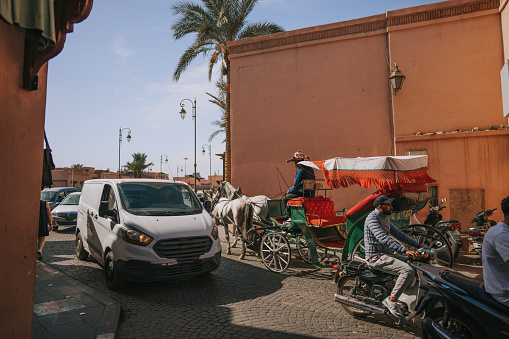 Busy road intersection in Marrakech , Morocco with horse carriage ,cars, motorcycle , on November 15th year 2022