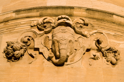 Indian elephant head carved from stone on the outside of the Indian Institute building, Oxford, England. Warm sunset light.