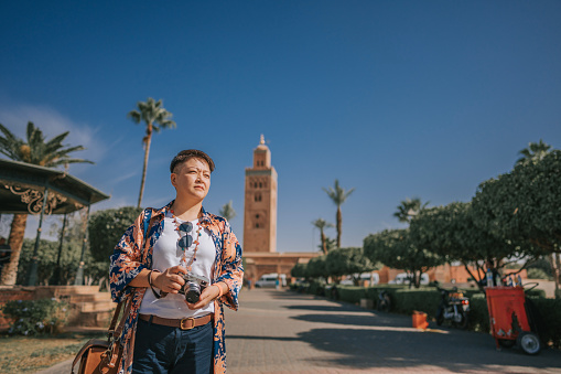 Asian Chinese tourist in front of Koutoubia Mosque looking away