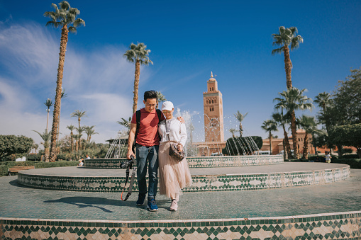 Asian Chinese tourist couple in front of fountain , Koutoubia Mosque, Morocco
