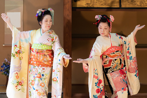 Two elderly Japanese woman, with hair ornament, in flower-patterned kimono, dancing Japanese traditional dance in Japanese room